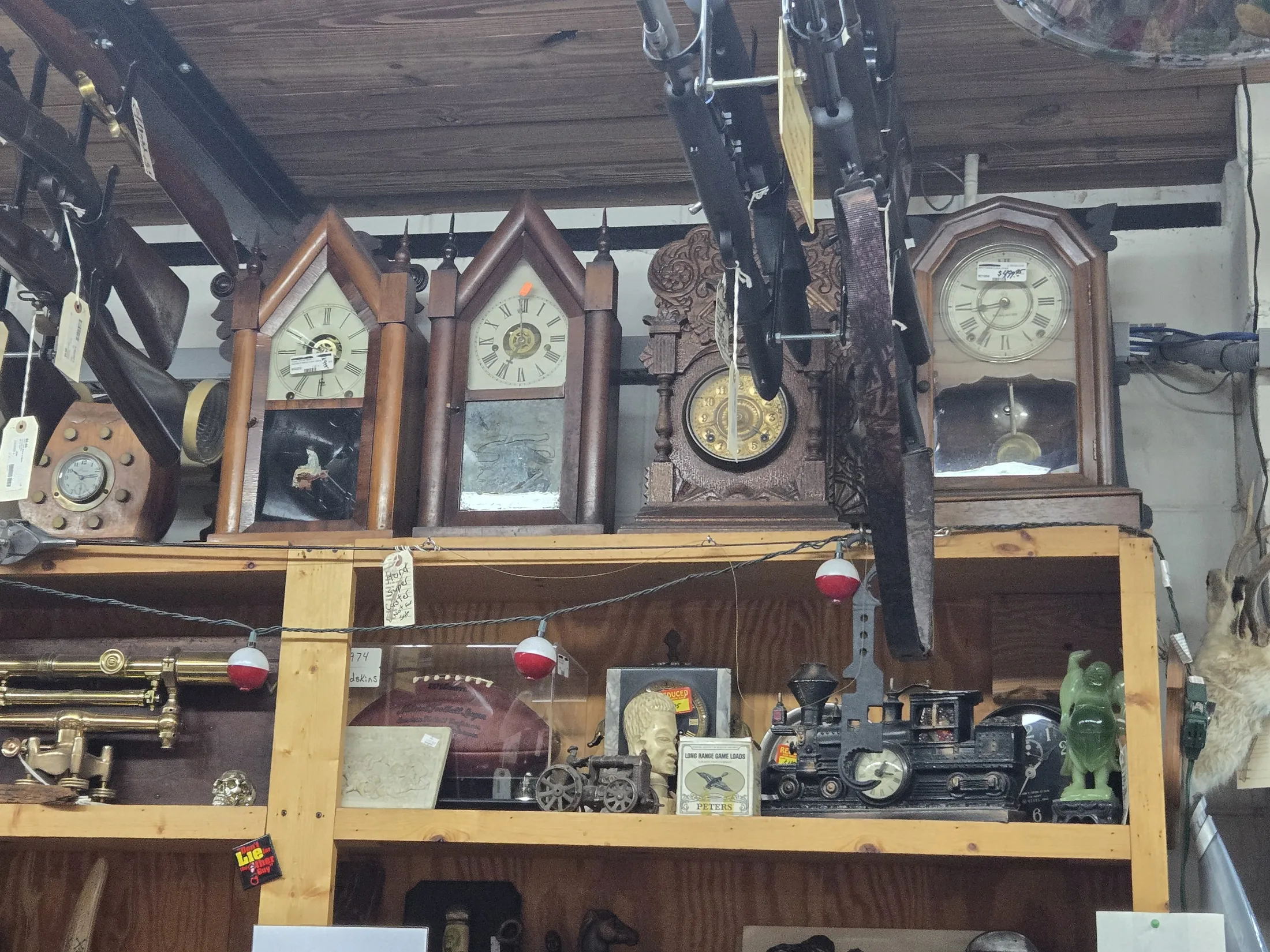 Antique mantel clocks and collectibles on a wooden shelf at AAA Gun & Pawn