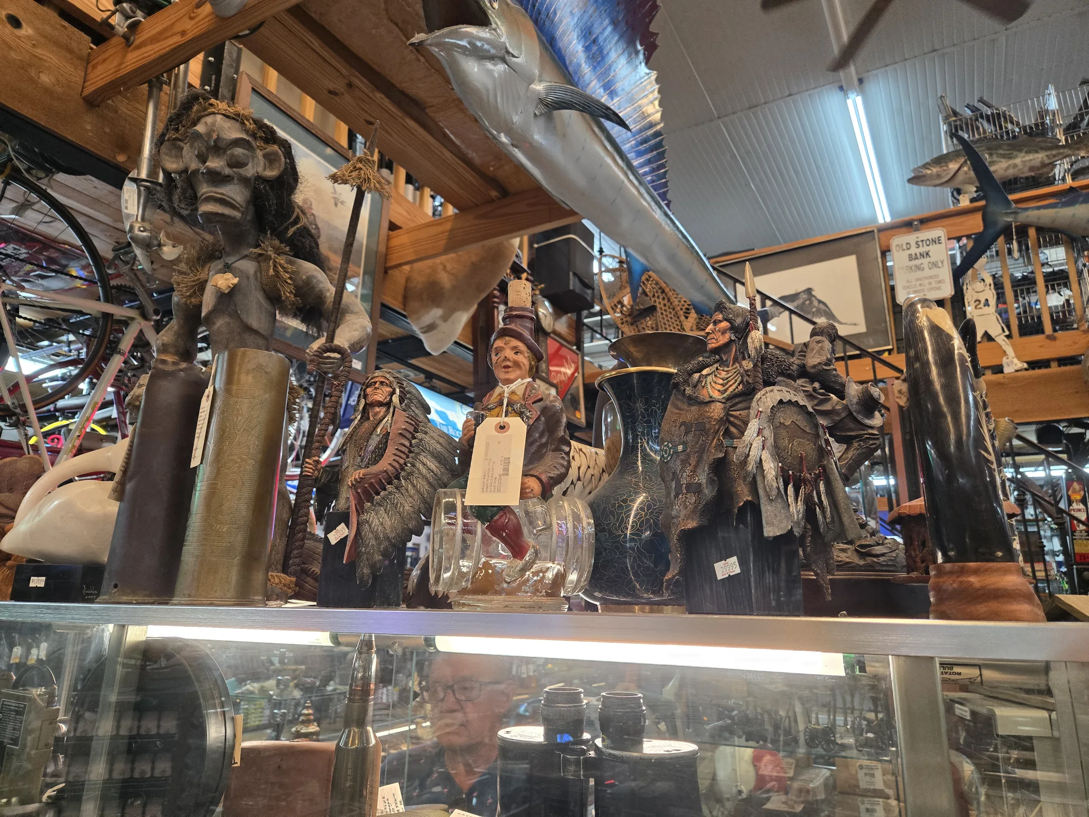 Figurines and carvings on a showcase with a mounted marlin overhead at AAA Gun & Pawn