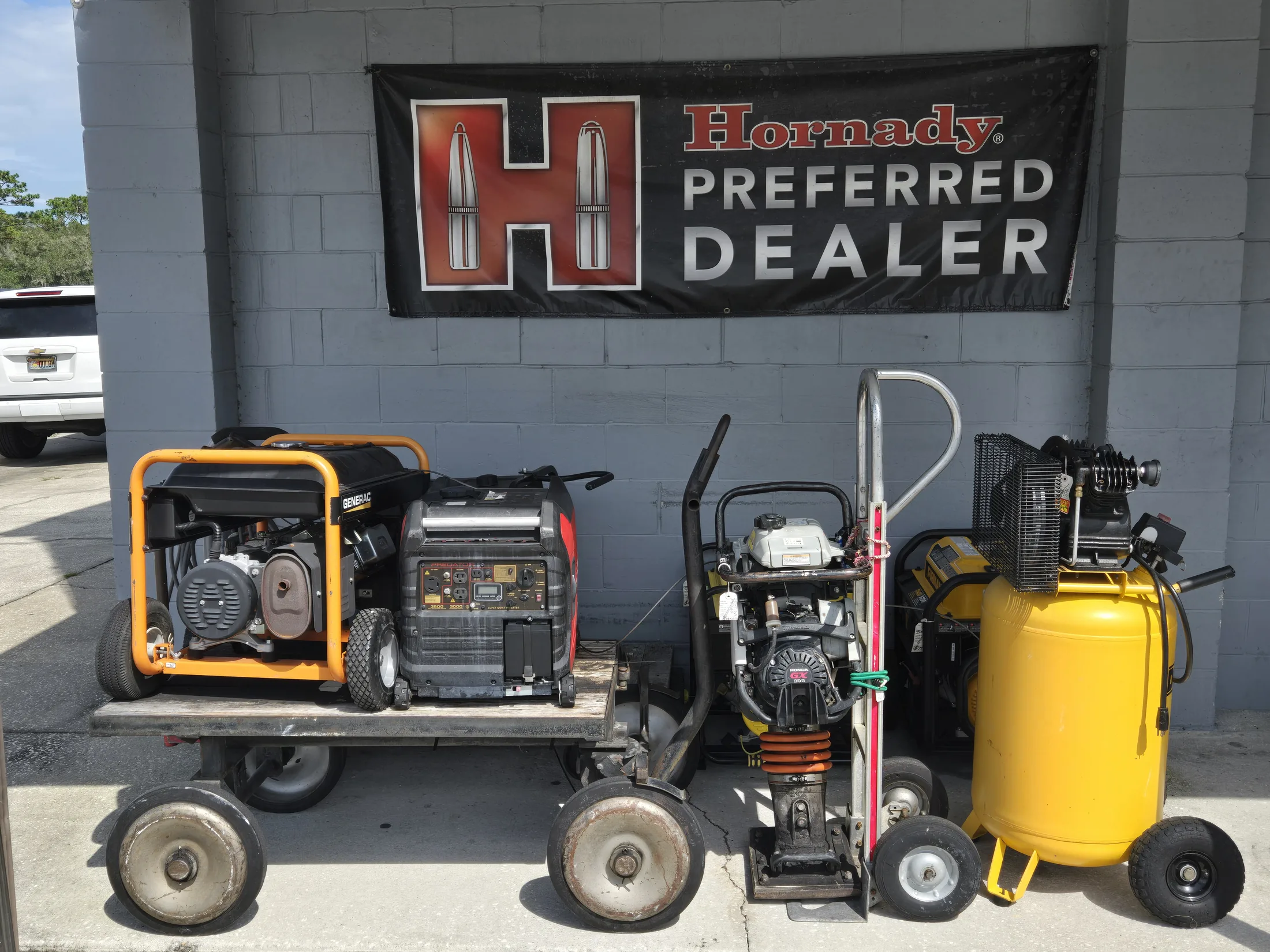 Generators and an air compressor outside AAA Gun & Pawn beneath the Hornady dealer banner