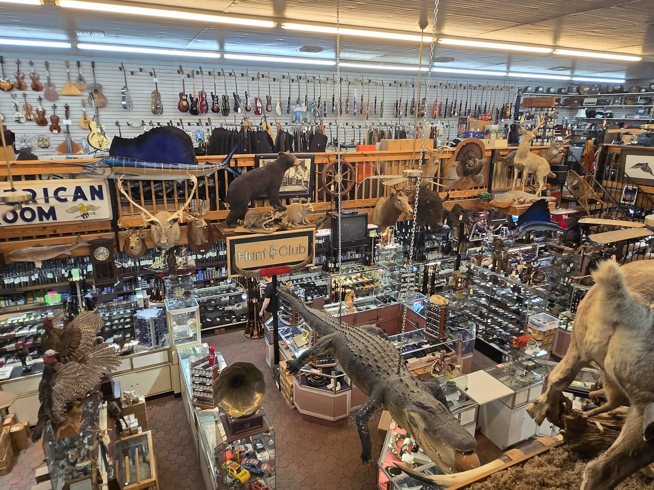 Sales floor at AAA Gun & Pawn with wildlife mounts, saddles and a wall of guitars