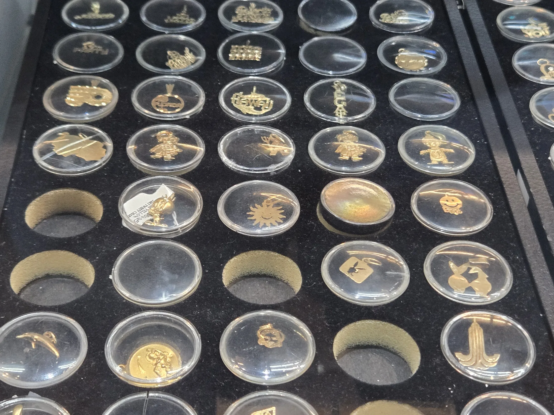 Tray of gold charms in the jewelry showcase at AAA Gun & Pawn