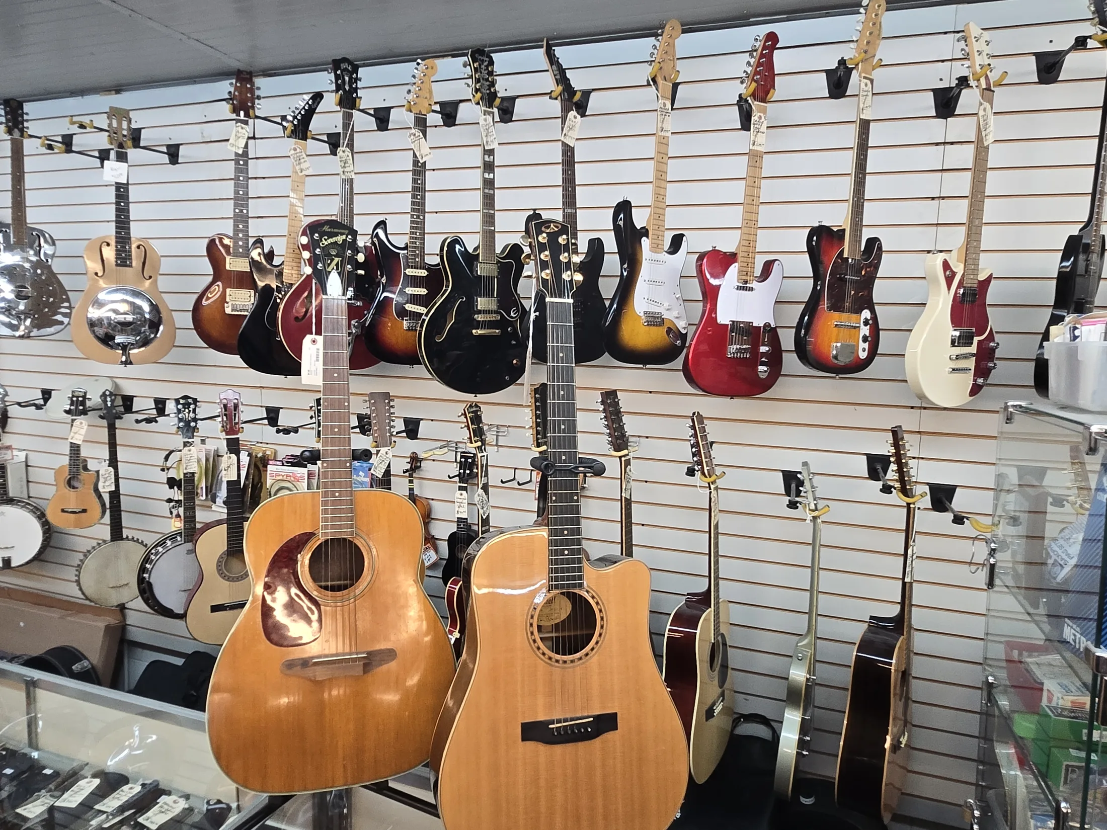 Acoustic and electric guitars hanging on the wall at AAA Gun & Pawn