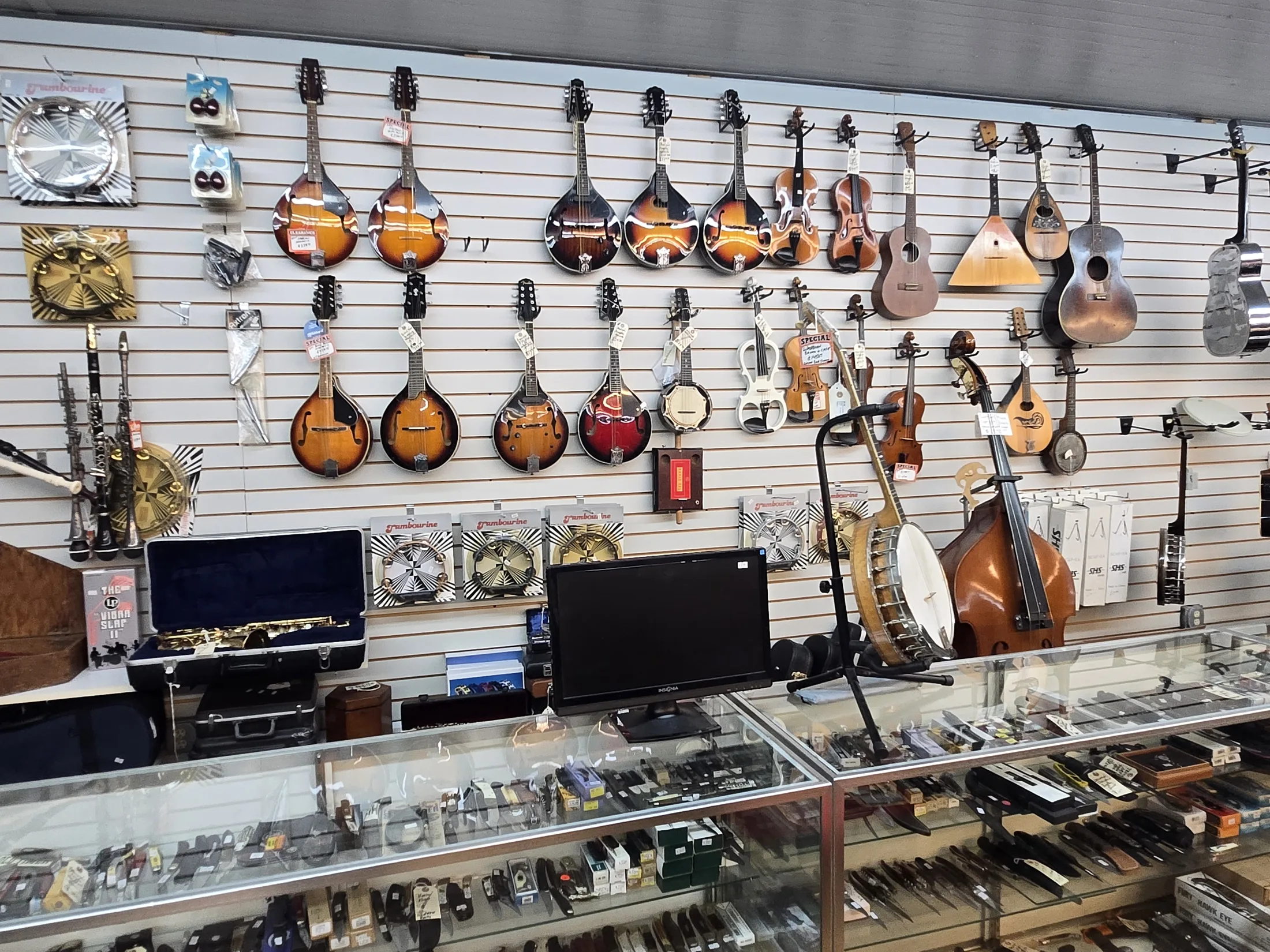 Mandolins, banjos and other stringed instruments hanging on a wall at AAA Gun & Pawn