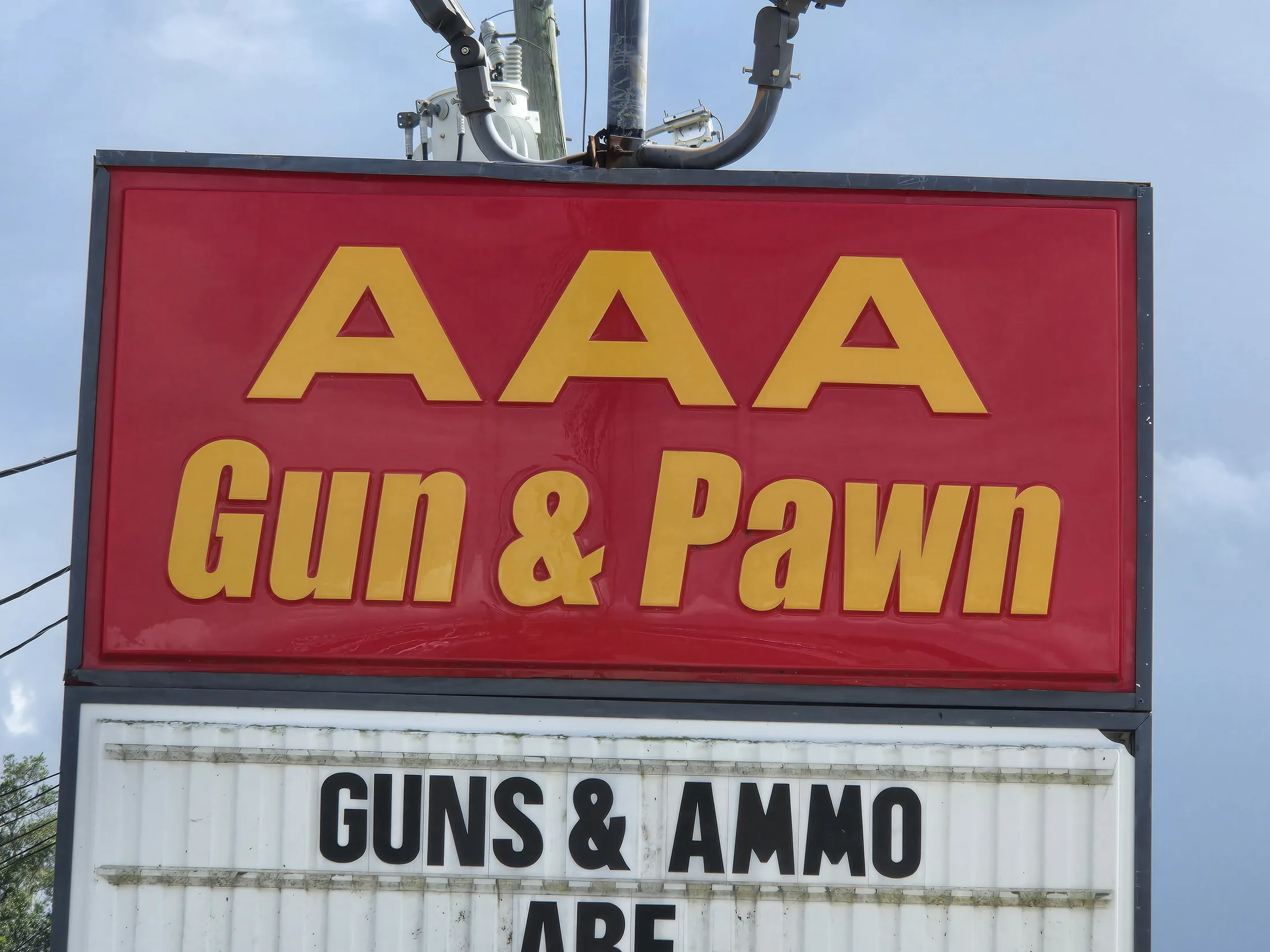 AAA Gun & Pawn roadside sign against a blue sky