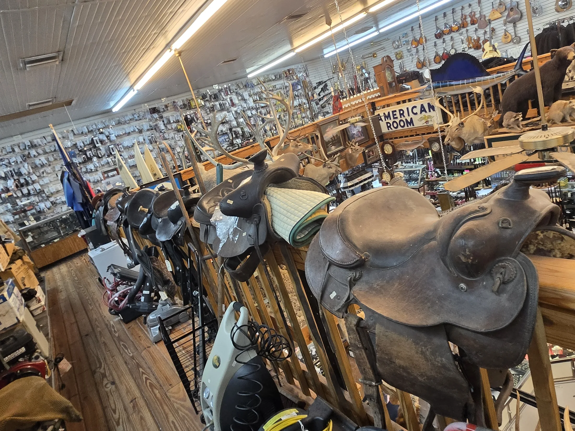 Western saddles on rails with the guitar wall behind at AAA Gun & Pawn